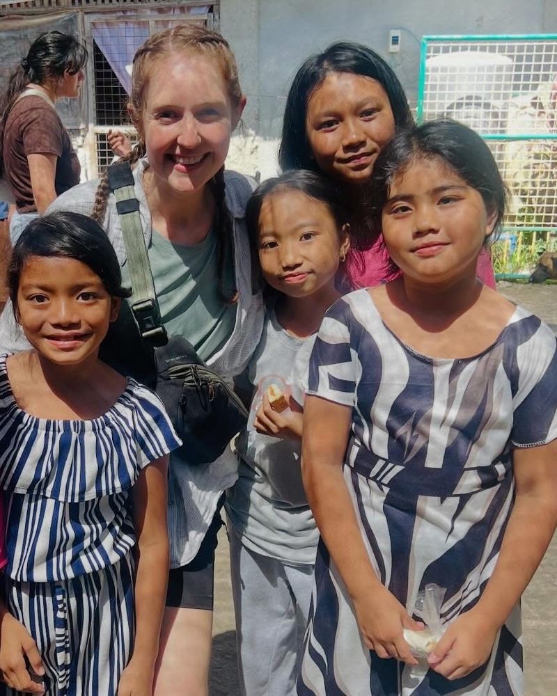 A team member surrounded by smiling children at a community outreach