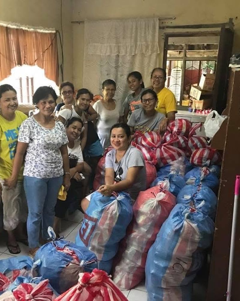 Volunteers standing with bundles of rice and groceries prepared for families
