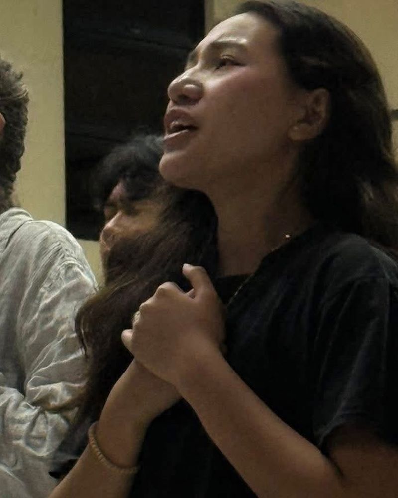 A woman worshipping with her eyes closed and hands over her heart